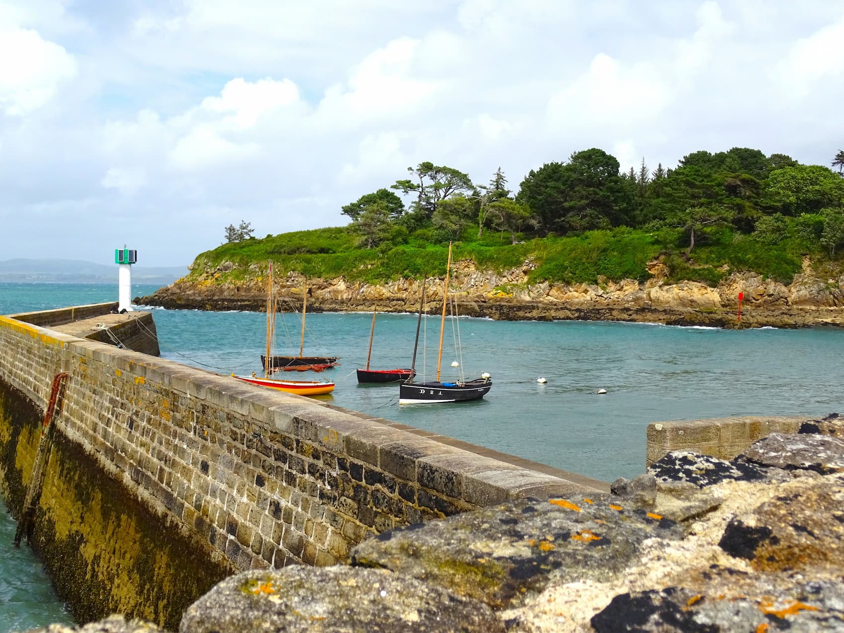 La cale et son phare dans le Finistère Sud, avec des bateaux traditionnels au mouillage