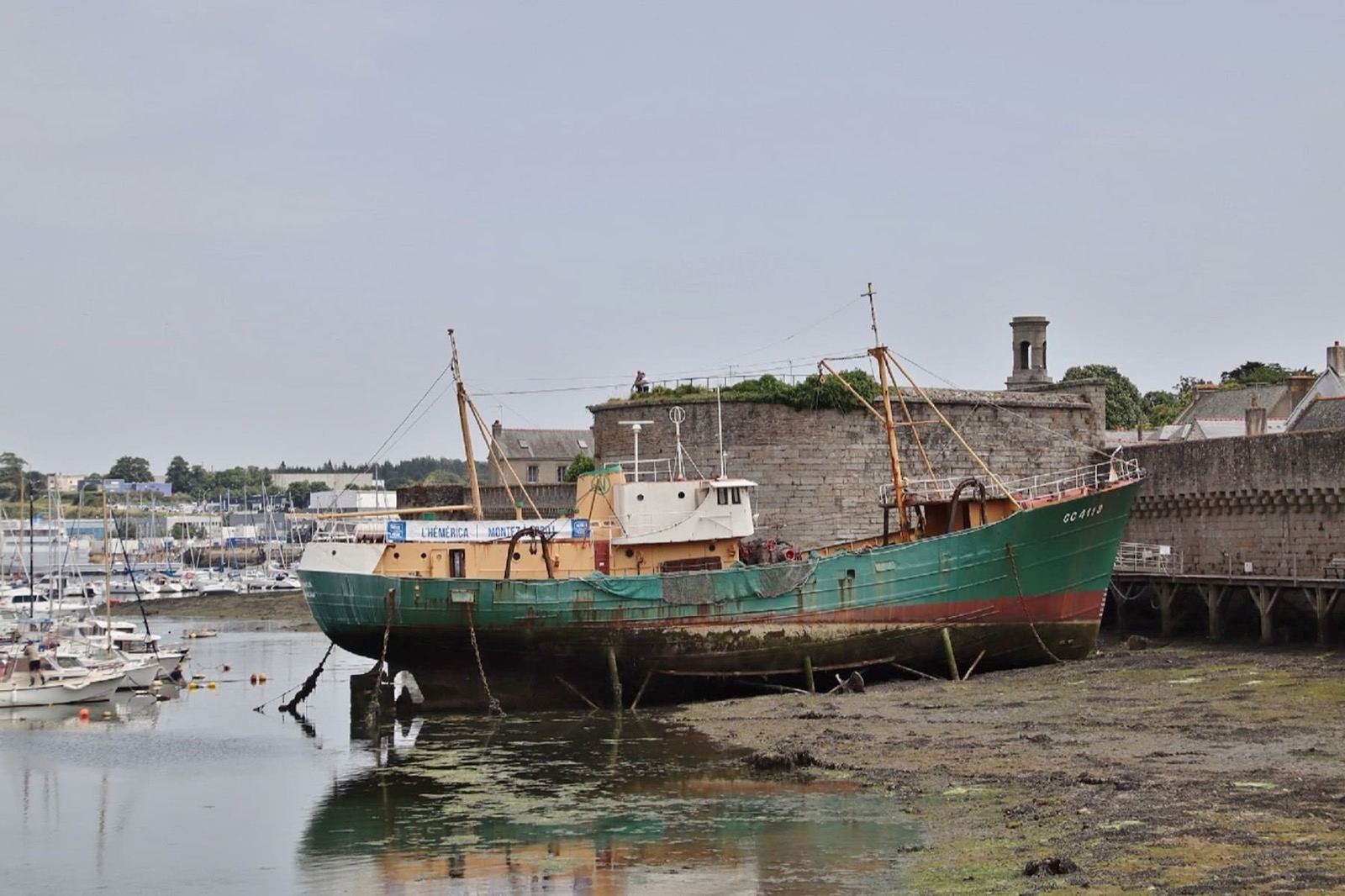 Chalutier échoué à marée basse dans le port de Concarneau devant les remparts de la Ville close, sous un ciel couvert