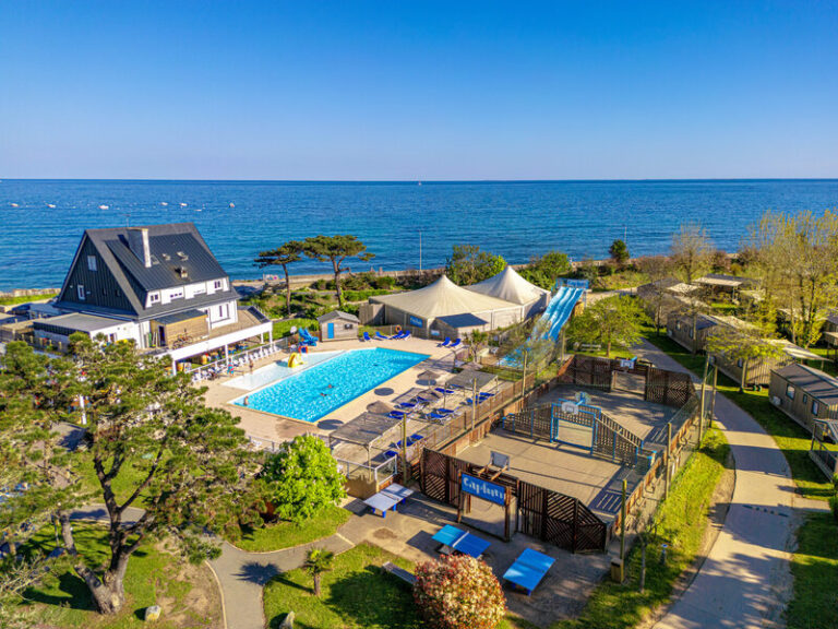 Vue aérienne du camping du Grand Large à Mousterlin, piscine, toboggans et mobil-homes face à la mer